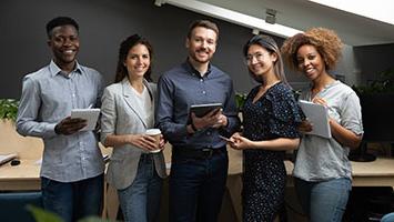 Group portrait of smiling multiethnic millennial work team standing together looking at camera in office, happy young multiracial diverse colleagues posing for picture show unity and partnership